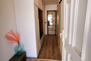 Inspiration pour une très grande entrée minimaliste avec un couloir, un mur blanc, un sol en vinyl, une porte simple et un sol marron.
