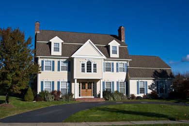 Photo of a large traditional three-storey yellow house exterior in Bridgeport with wood siding, a gambrel roof and a shingle roof.