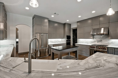 Large minimalist u-shaped medium tone wood floor kitchen photo in Other with a farmhouse sink, beaded inset cabinets, gray cabinets, marble countertops, stone slab backsplash, stainless steel appliances and an island