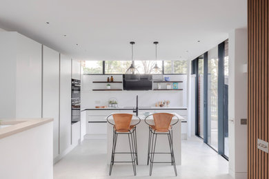 Design ideas for a contemporary l-shaped open plan kitchen in London with flat-panel cabinets, white cabinets, composite countertops, an island and white worktops.