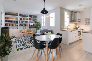 This is an example of a mid-sized scandinavian open plan dining in Madrid with white walls, light hardwood floors, no fireplace and beige floor.