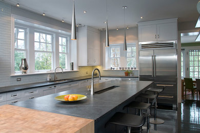 Large trendy eat-in kitchen photo in Philadelphia with white cabinets, white backsplash, stainless steel appliances, glass tile backsplash, an island, an undermount sink, soapstone countertops, black countertops and shaker cabinets