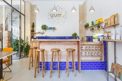 Cette image montre une cuisine ouverte design en U de taille moyenne avec un plan de travail en bois, une crédence bleue, une crédence en céramique et un évier encastré.