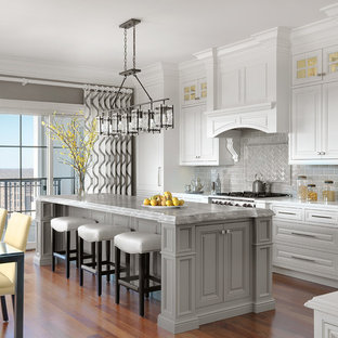 Imagen de cocina comedor tradicional, grande, con armarios con paneles con relieve, puertas de armario blancas, encimera de mármol, salpicadero verde, salpicadero de azulejos tipo metro, suelo de madera en tonos medios, una isla, electrodomésticos con paneles y encimeras grises