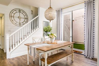 Example of a country medium tone wood floor and brown floor dining room design in Orange County with white walls