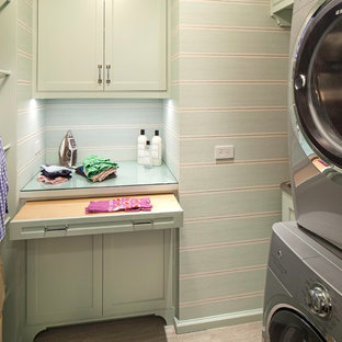 Small classic separated utility room in New York with an utility sink, green cabinets, glass worktops, green walls, ceramic flooring and a stacked washer and dryer.