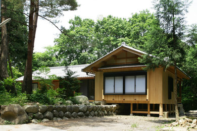 This is an example of an asian brown exterior in Other with wood siding, a gable roof and a tile roof.