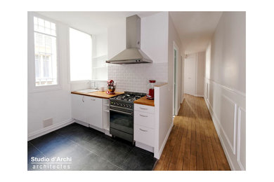 Cette image montre une cuisine ouverte parallèle traditionnelle de taille moyenne avec un plan de travail en bois, une crédence bleue, une crédence en céramique, un sol en carrelage de céramique et un sol gris.