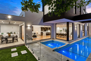 Photo of a large backyard rectangular lap pool in Sydney with a hot tub and concrete pavers.