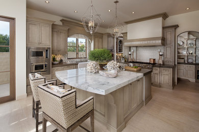 Design ideas for a large beach style kitchen in Orange County with a farmhouse sink, recessed-panel cabinets, light wood cabinets, marble benchtops, white splashback, stainless steel appliances, light hardwood floors and with island.