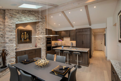 Mid-sized trendy l-shaped light wood floor, brown floor and vaulted ceiling open concept kitchen photo in Indianapolis with an undermount sink, flat-panel cabinets, dark wood cabinets, granite countertops, beige backsplash, porcelain backsplash, paneled appliances, an island and brown countertops