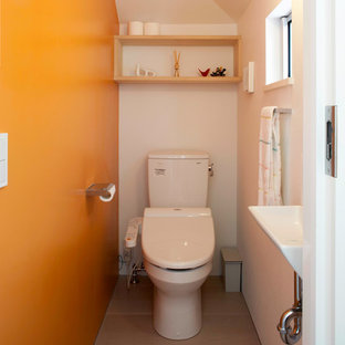 Foto di un bagno di servizio minimalista di medie dimensioni con ante a filo, ante in legno chiaro, WC monopezzo, pareti arancioni, pavimento in compensato, lavabo sottopiano, pavimento beige e top bianco