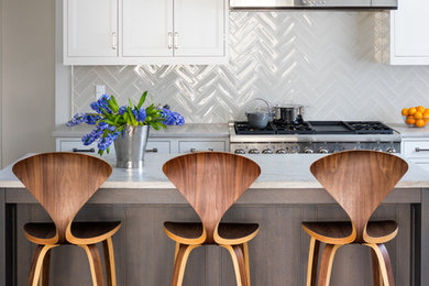 Inspiration for a mid-sized timeless single-wall dark wood floor open concept kitchen remodel in New York with a drop-in sink, recessed-panel cabinets, white cabinets, granite countertops, white backsplash, glass tile backsplash, stainless steel appliances and an island