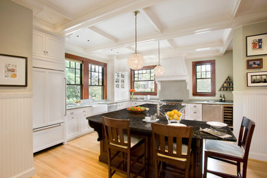 Traditional l-shaped kitchen in Boston with a farmhouse sink, recessed-panel cabinets, white cabinets, stainless steel appliances, medium hardwood floors and with island.