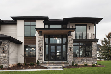 Example of a large minimalist beige two-story concrete fiberboard and clapboard house exterior design in Chicago with a hip roof, a shingle roof and a black roof