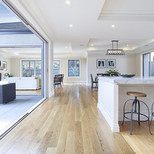 Idée de décoration pour une grande arrière-cuisine linéaire tradition avec un évier 2 bacs, un placard à porte persienne, un plan de travail en quartz modifié, une crédence blanche, une crédence en carrelage de pierre, un électroménager blanc, un sol en bois clair et un îlot central.