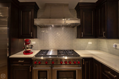 Eat-in kitchen - mid-sized transitional l-shaped medium tone wood floor and brown floor eat-in kitchen idea in Chicago with a farmhouse sink, raised-panel cabinets, dark wood cabinets, quartzite countertops, gray backsplash, porcelain backsplash, stainless steel appliances, an island and multicolored countertops