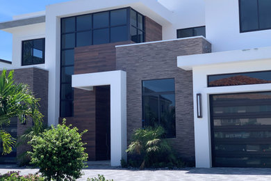 Mid-sized minimalist white two-story stone exterior home photo in Miami with a gray roof