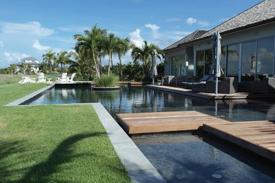 Example of a large island style backyard rectangular lap pool design in Miami with decking