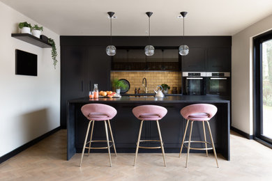 Inspiration for a medium sized contemporary cream and black galley open plan kitchen in Other with flat-panel cabinets, black cabinets, granite worktops, metallic splashback, black appliances, laminate floors, an island, beige floors, black worktops, a coffered ceiling, feature lighting and a submerged sink.