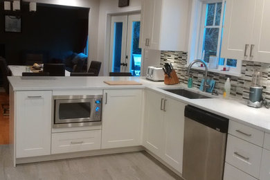 Kitchen - mid-sized transitional l-shaped porcelain tile kitchen idea in Vancouver with an undermount sink, shaker cabinets, white cabinets, quartz countertops, multicolored backsplash, mosaic tile backsplash, stainless steel appliances and a peninsula