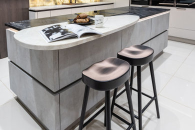 Inspiration for a large contemporary cream and black l-shaped kitchen/diner in West Midlands with an integrated sink, flat-panel cabinets, dark wood cabinets, granite worktops, multi-coloured splashback, marble splashback, black appliances, porcelain flooring, an island, beige floors, black worktops and a feature wall.