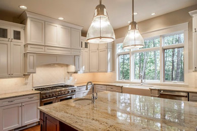 Kitchen - large traditional medium tone wood floor kitchen idea in Minneapolis with white cabinets, white backsplash, ceramic backsplash, stainless steel appliances and an island