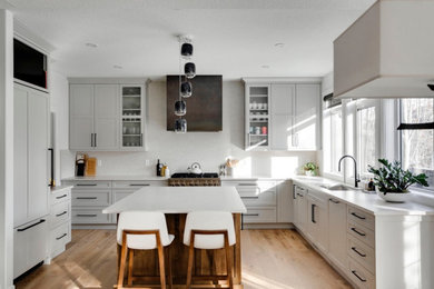 Example of a large minimalist u-shaped light wood floor eat-in kitchen design in Calgary with an undermount sink, shaker cabinets, gray cabinets, quartz countertops, white backsplash, quartz backsplash, paneled appliances, an island and white countertops
