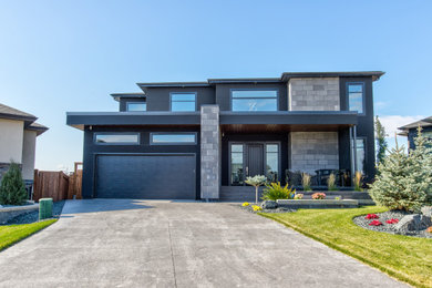 Contemporary two-storey stucco black house exterior in Other with a hip roof, a shingle roof and a black roof.