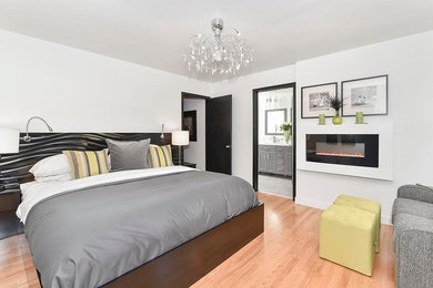 Trendy master light wood floor bedroom photo in Calgary with white walls and a ribbon fireplace