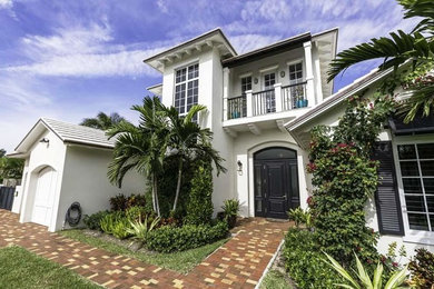 Inspiration for a large tropical white two-story stucco gable roof remodel in Miami