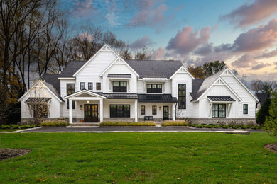 Modelo de fachada de casa blanca y gris grande de tres plantas con revestimientos combinados, tejado de teja de madera y panel y listón