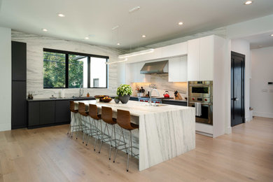 Imagen de cocinas en L moderna abierta con fregadero bajoencimera, armarios con paneles lisos, electrodomésticos de acero inoxidable y una isla