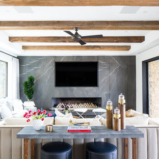 Großes, Offenes Mediterranes Wohnzimmer mit weißer Wandfarbe, braunem Holzboden, Kamin, Kaminsims aus Stein, Multimediawand und braunem Boden in Orange County