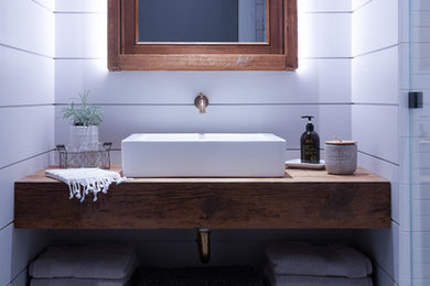 Inspiration for a small country 3/4 white tile and subway tile mosaic tile floor and black floor walk-in shower remodel in New York with medium tone wood cabinets, a one-piece toilet, white walls, a vessel sink and a hinged shower door
