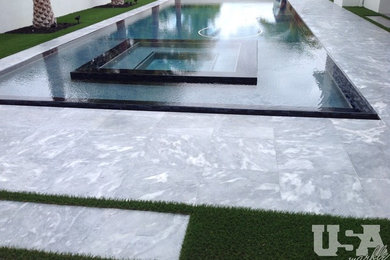 Mid-sized modern backyard rectangular infinity pool in Miami with a hot tub and natural stone pavers.