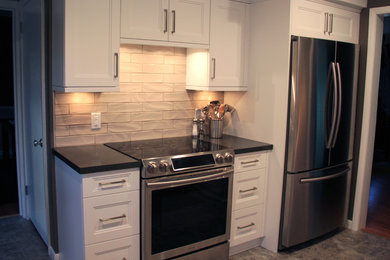 Example of a mid-sized transitional galley vinyl floor and gray floor enclosed kitchen design in Minneapolis with a double-bowl sink, white cabinets, laminate countertops, beige backsplash, ceramic backsplash, stainless steel appliances, no island and recessed-panel cabinets