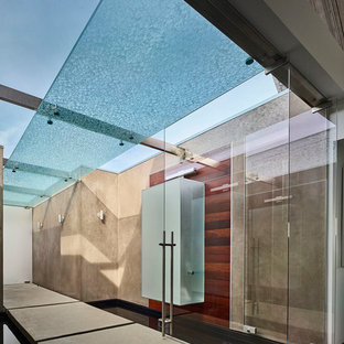 На фото: большие фойе в стиле ретро с серыми стенами, бетонным полом, поворотной входной дверью, стеклянной входной дверью и серым полом