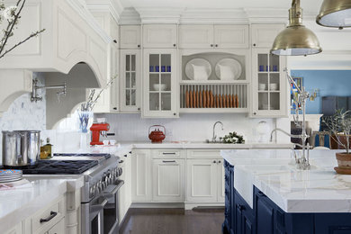 Inspiration for a traditional l-shaped kitchen in Los Angeles with white cabinets, with island, a farmhouse sink, recessed-panel cabinets, stainless steel appliances, dark hardwood floors, brown floor and white benchtop.