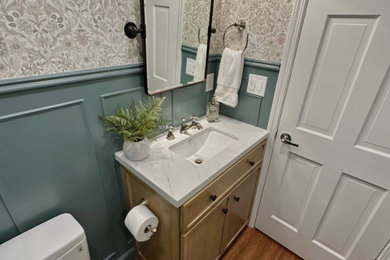 Example of a small classic green tile and subway tile medium tone wood floor powder room design in Phoenix with flat-panel cabinets, light wood cabinets, a two-piece toilet, green walls, an undermount sink, quartz countertops, white countertops and a freestanding vanity