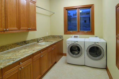 Design ideas for a mid-sized traditional single-wall laundry room in Dallas with an undermount sink, recessed-panel cabinets, medium wood cabinets, granite benchtops, beige walls, ceramic floors, a side-by-side washer and dryer and beige floor.