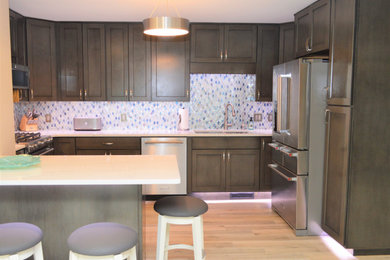 シカゴにある中くらいなコンテンポラリースタイルのおしゃれなキッチン (アンダーカウンターシンク、シェーカースタイル扉のキャビネット、中間色木目調キャビネット、珪岩カウンター、青いキッチンパネル、セラミックタイルのキッチンパネル、シルバーの調理設備、淡色無垢フローリング、茶色い床、白いキッチンカウンター) の写真