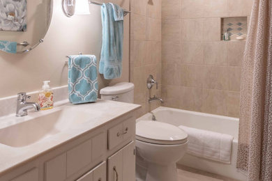 Bathroom - small transitional kids' beige tile and ceramic tile ceramic tile, beige floor and single-sink bathroom idea in Other with beaded inset cabinets, white cabinets, a one-piece toilet, beige walls, an integrated sink, solid surface countertops, multicolored countertops, a niche and a built-in vanity