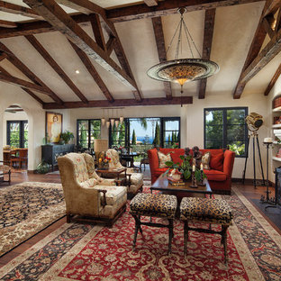 Foto de salón con barra de bar cerrado, mediterráneo, grande, sin televisor, con paredes beige, chimenea tradicional, marco de chimenea de yeso y suelo de madera en tonos medios