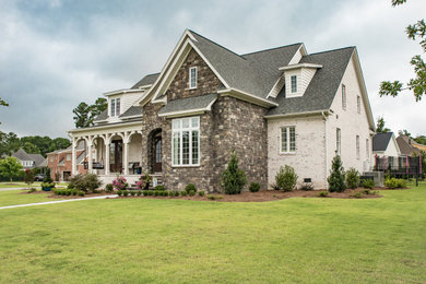 Large elegant white two-story brick and shingle house exterior photo in Other with a shingle roof and a gray roof