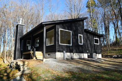 Inspiration for a mid-sized 1950s black one-story wood exterior home remodel in New York with a shed roof
