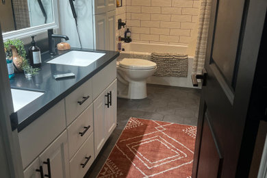 Tub/shower combo - modern kids' beige tile double-sink tub/shower combo idea with white cabinets, solid surface countertops, black countertops and a freestanding vanity
