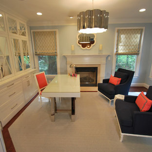 This is an example of a medium sized modern study in DC Metro with blue walls, medium hardwood flooring, a standard fireplace, a wooden fireplace surround, a freestanding desk and brown floors.