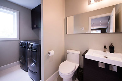 Utility room - small contemporary single-wall porcelain tile utility room idea in Other with flat-panel cabinets, dark wood cabinets, gray walls, a side-by-side washer/dryer and a single-bowl sink