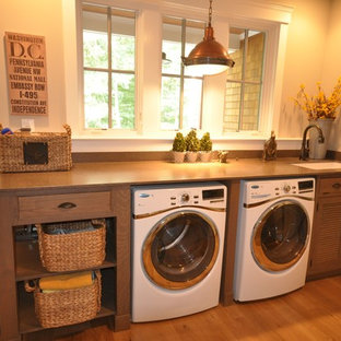 Photo of a small classic single-wall separated utility room in DC Metro with a submerged sink, louvered cabinets, medium wood cabinets, beige walls, light hardwood flooring, a side by side washer and dryer and beige floors.